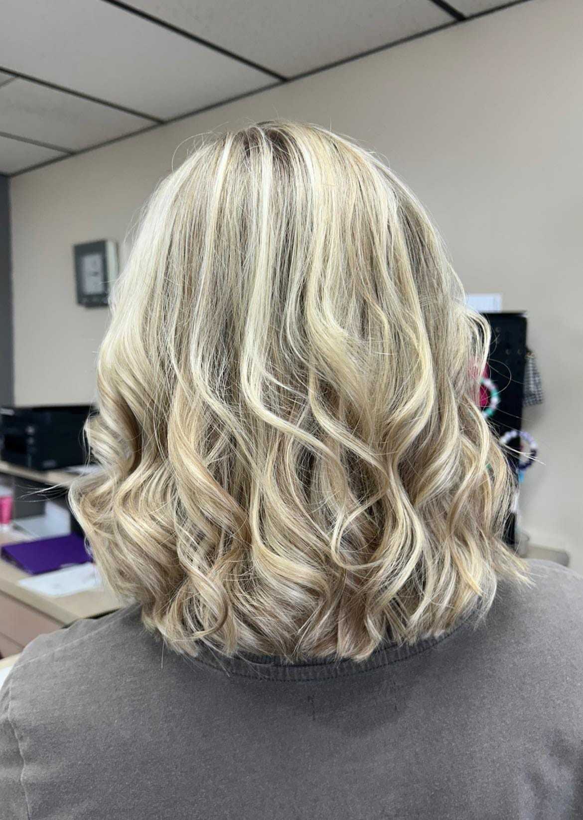 Blonde hair with soft curls from the back, showing a fresh haircut and style in a salon.