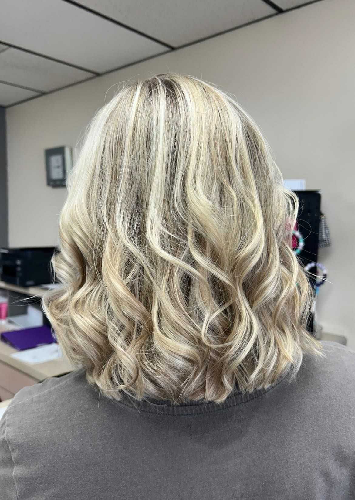 Blonde hair with soft curls from the back, showing a fresh haircut and style in a salon.