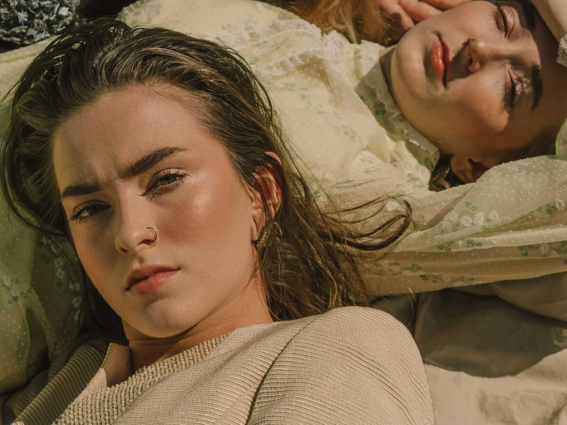 Three women lying on fabric, gazing thoughtfully at the camera.
